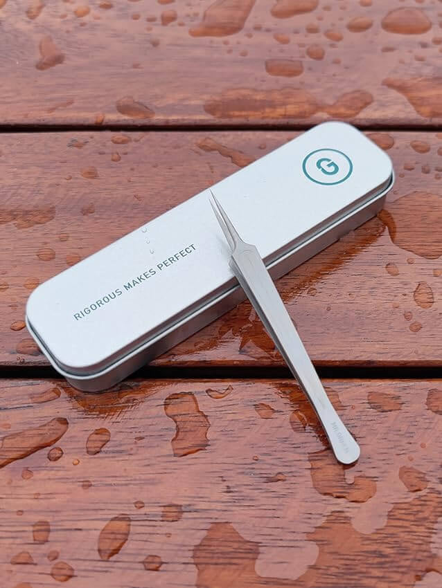 MR.GREEN stainless slanted ingrown hair tweezers with precision tip beside metal travel case — professional eyebrow & splinter remover